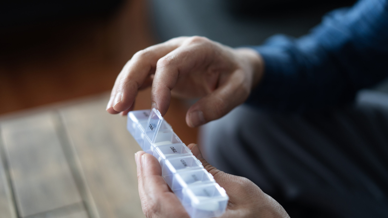 Close up of senior man's hands opening daily pill organizer