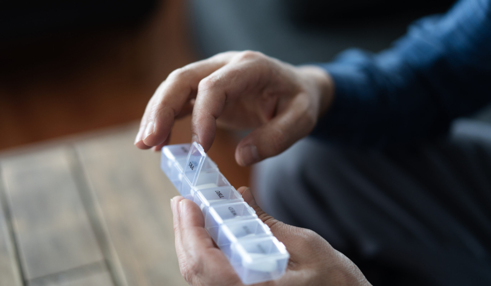 Close up of senior man's hands opening daily pill organizer