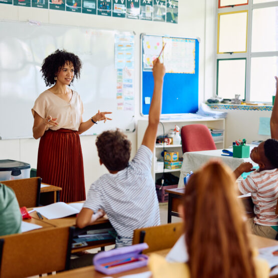Teacher in classroom with student raising hand.