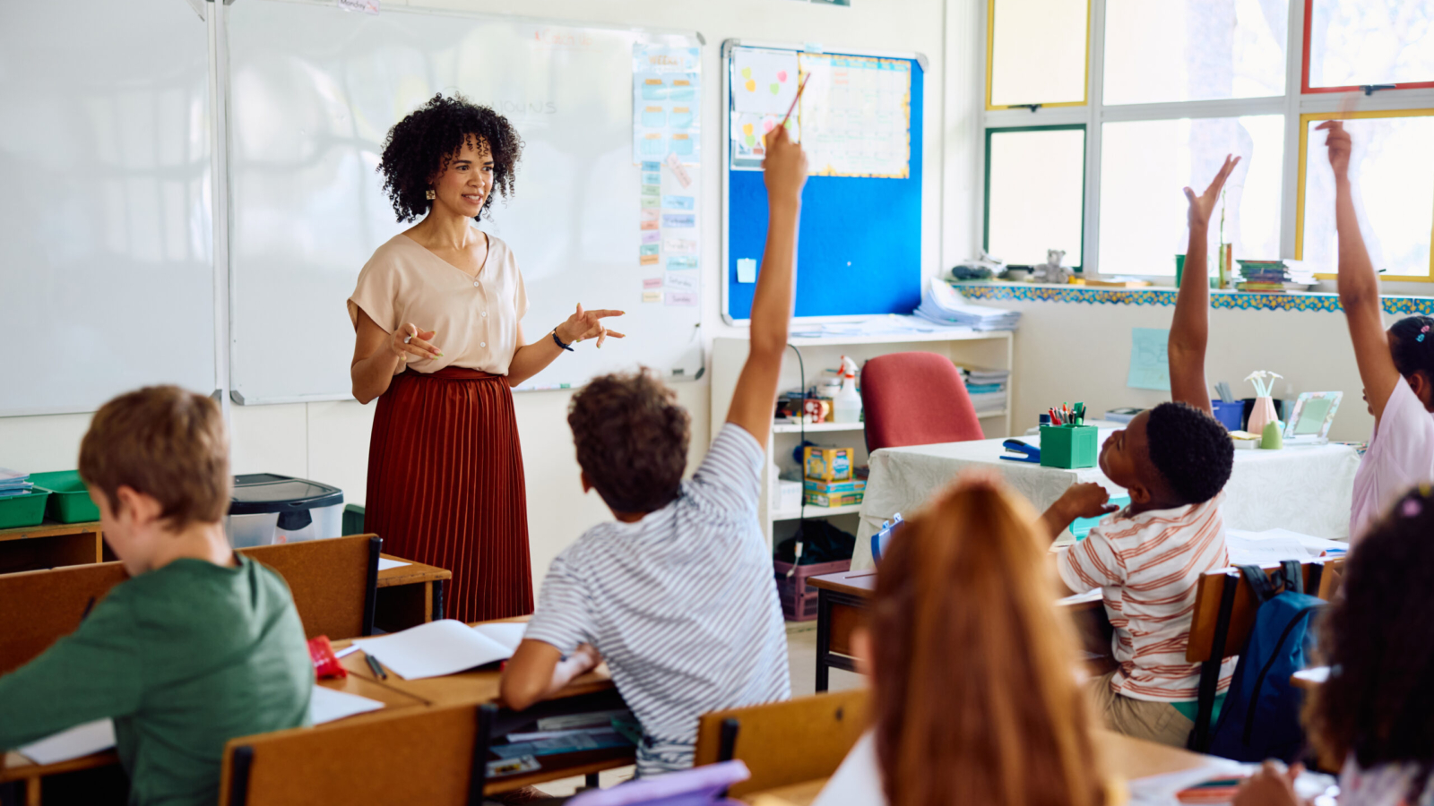Teacher in classroom with student raising hand.