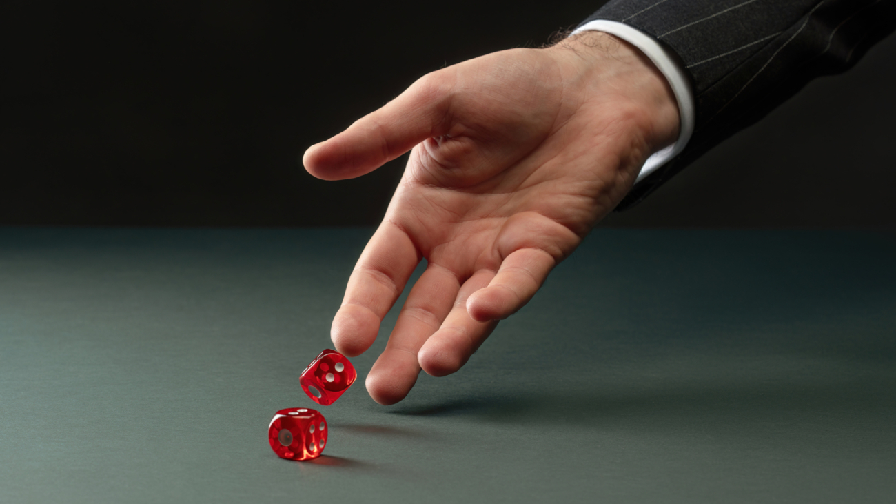 caucasian hand rolling two red dice representing how pharmacy benefit costs are risky.