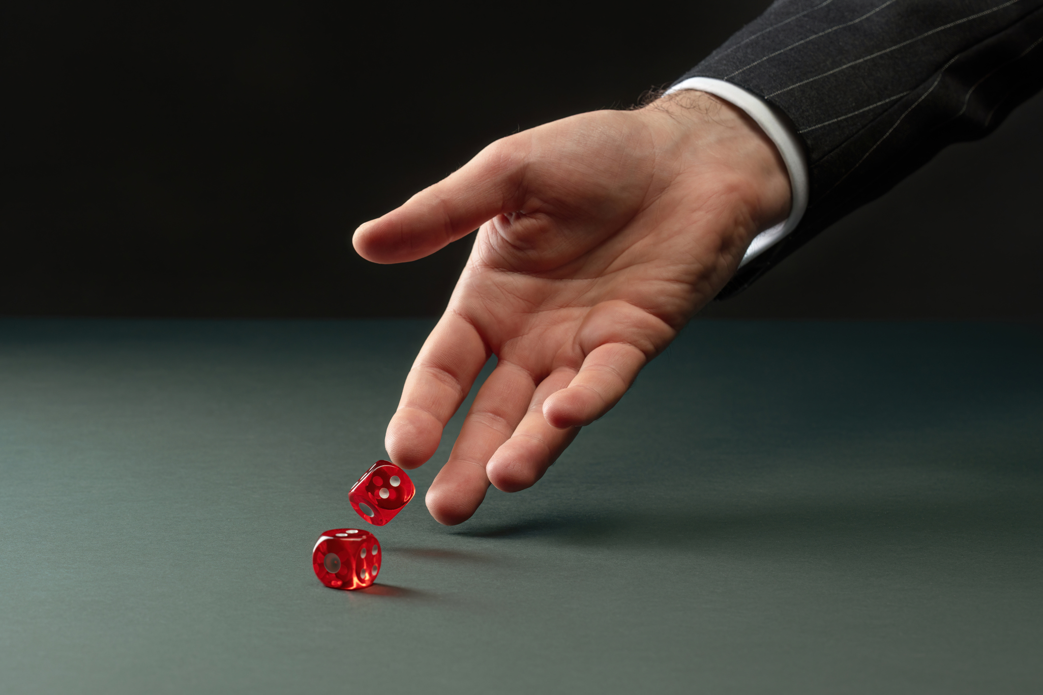 caucasian hand rolling two red dice representing how pharmacy benefit costs are risky.